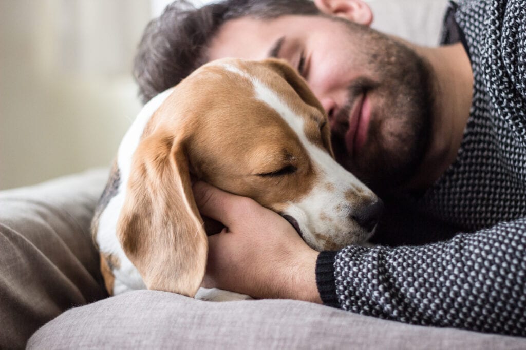 man snuggling dog